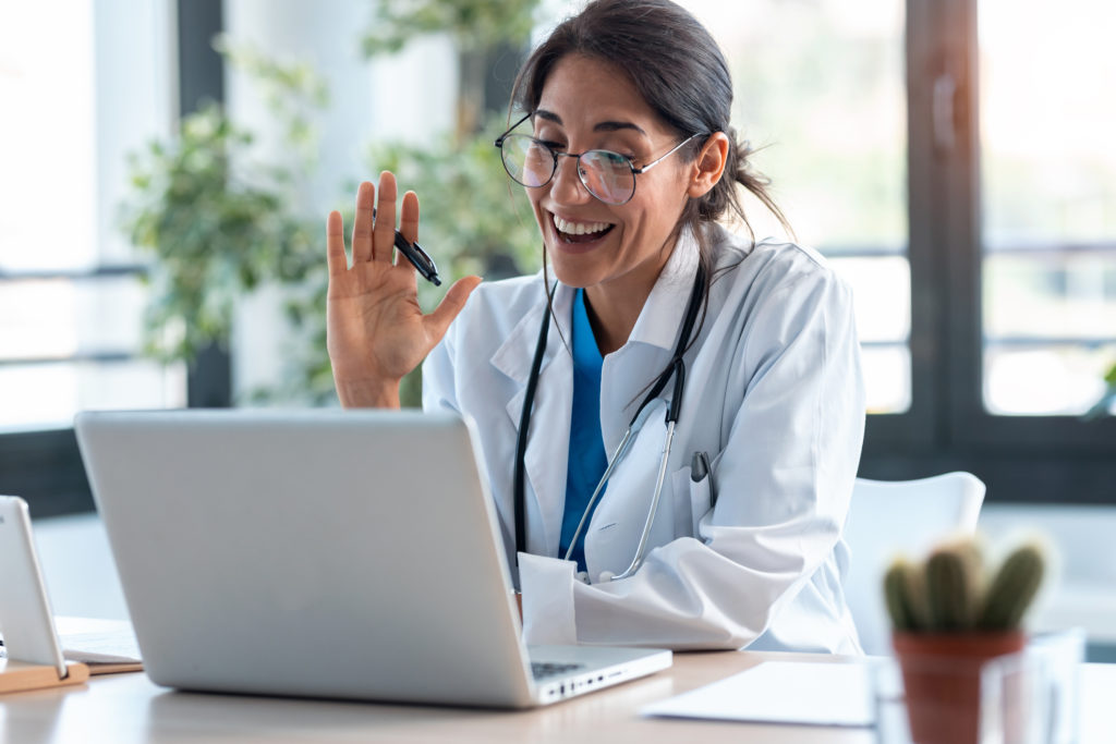 Family doctor waving to computer virtual call